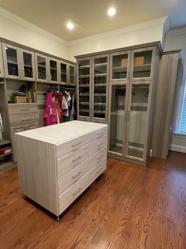 A walk-in closet with a dresser and cabinets, providing ample storage space for clothing and accessories.