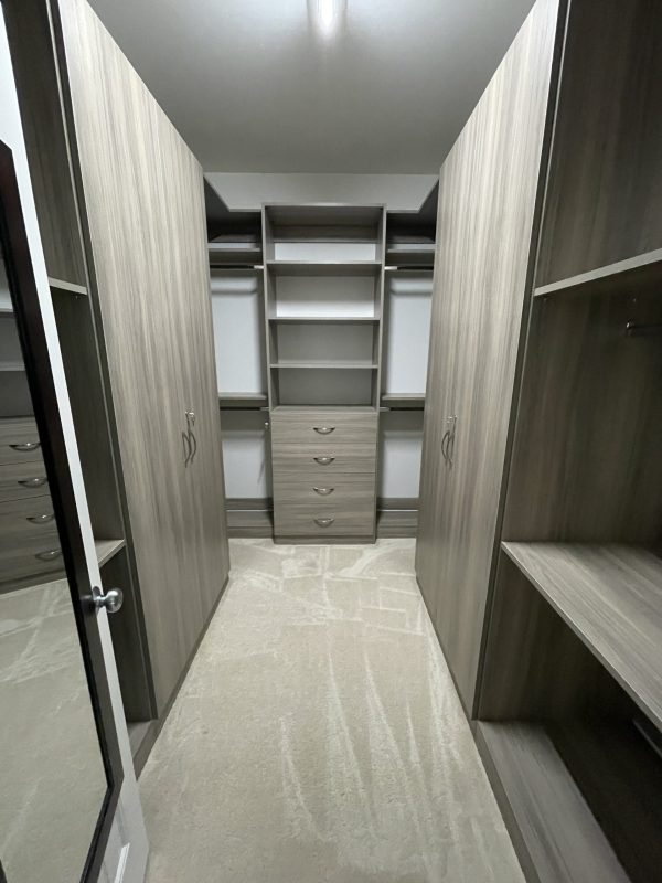 Interior of a walk-in closet with shelves and cabinets, neatly organized and spacious.