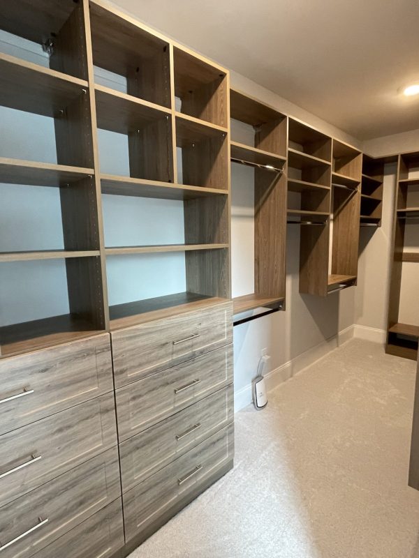 A well-organized walk-in closet with neatly arranged shelves and drawers for storing clothes and accessories.