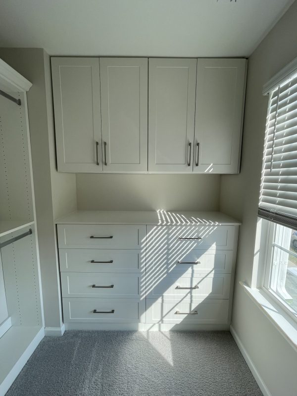 A room with white cabinets and a window, providing a bright and clean space for various activities.