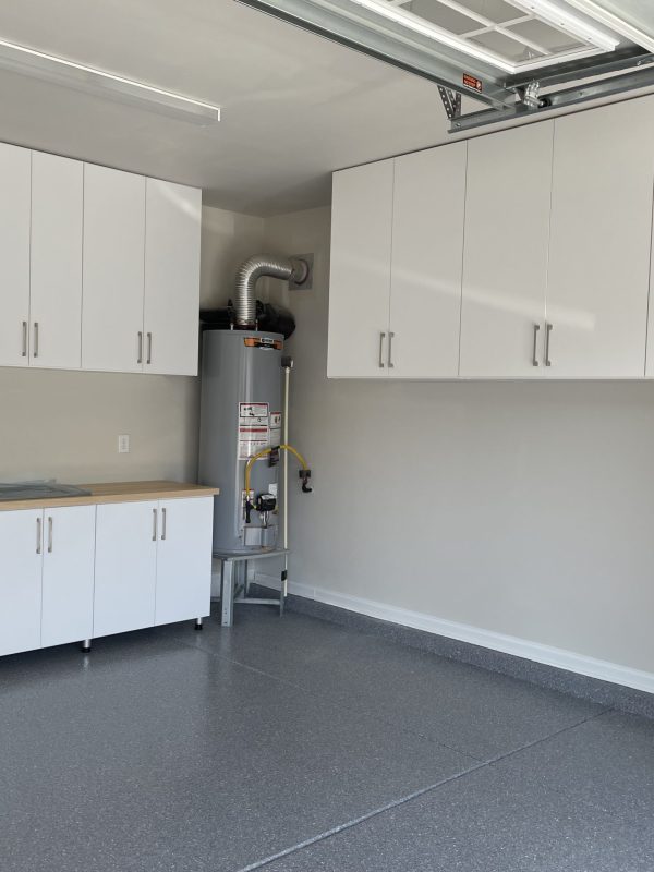 A garage with white cabinets and a sink, providing storage and utility for various tools and equipment.