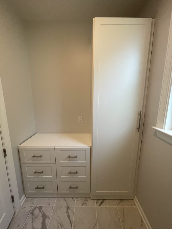 A white cabinet with drawers and a window, providing storage and natural light.